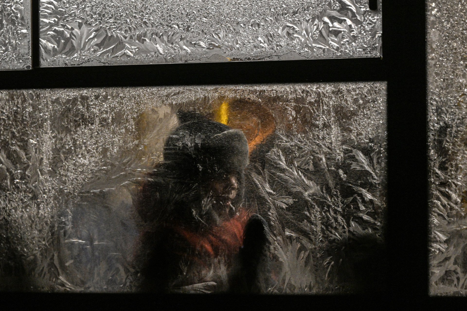 A youth scrapes frost from a frozen bus window in Kyiv on the evening of Jan. 15, 2026, amid Russia’s invasion of Ukraine. (Photo: Getty Images)