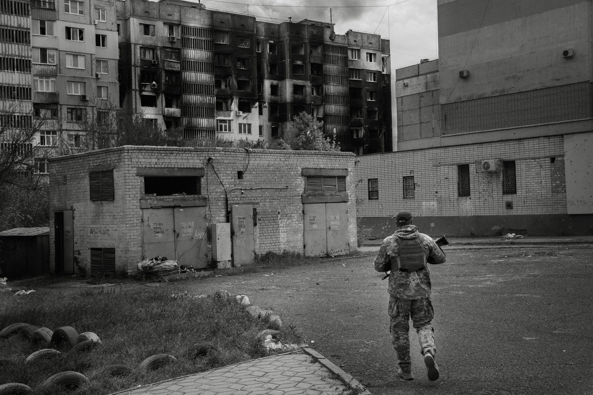 Serhii patrols as a destroyed residential housing block looms in the background. Kherson, Ukraine, May 2026. Photo: Joshua Olley / UNITED24 Media