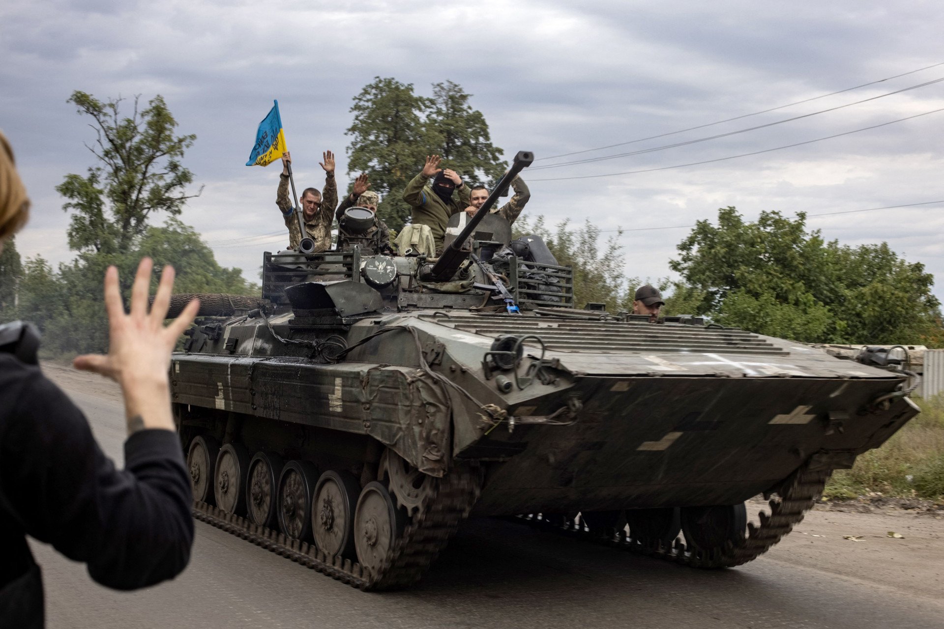 Local greets Ukrainian soldiers riding an armoured personnel carrier