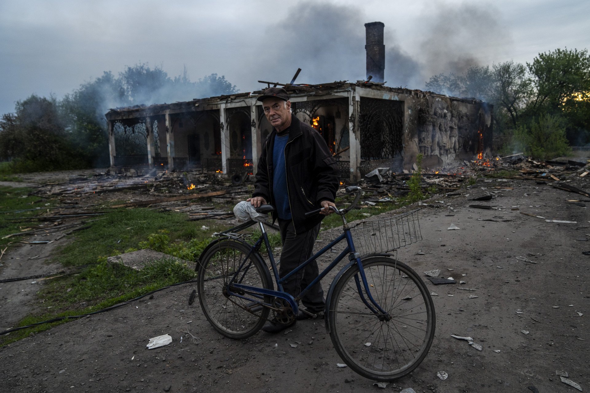A man on a bicycle stands in front of the destruction caused by a Shahed drone attack on the Ukrainian Red Cross base and “Petushok” cafe in Dobropillia, Pokrovsk district, Donetsk region, Ukraine on April 30, 2025. Photo by Jose Colon/Anadolu via Getty Images.