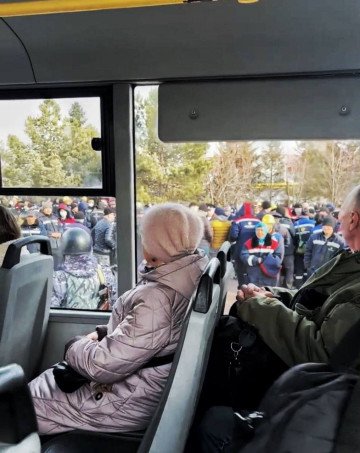 Security forces gather near a crowd of workers, as seen from inside a bus. (Source: Ostorozhno Novosti)