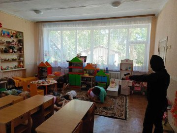 Children crouch on the floor during an anti-terrorism drill at a Russian kindergarten, while a participant portraying an attacker points a weapon inside the room. Similar exercises have been held across Russian schools and preschools. 