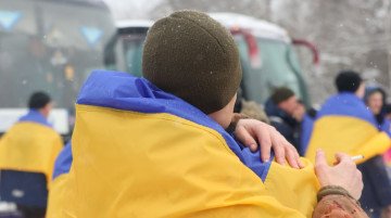A freed Ukrainian prisoner wrapped in the national flag. (Photo: Official channel of the President of Ukraine Volodymyr Zelenskyy)