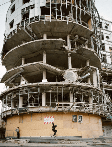 A skater attempts a trick beneath a destroyed building. (Photo: Hironori Kodama)