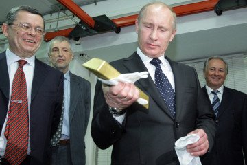 Russian leader Vladimir Putin holds a gold bar while visiting the Central Depository of the Bank of Russia next to Georgy Luntovsky (L), on January 24, 2011, in Moscow. (Source: Getty Images)