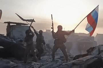 Russian soldiers pose with a Russian flag amid destroyed buildings in footage published online. (Photo: Open source) Russian soldiers pose with a Russian flag amid destroyed buildings in footage published online. (Photo: Open source)