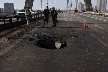 Police officers look at the damages following a Russian drone strike on the Northern Bridge in Kyiv on October 4, 2026. (Source: Getty Images)