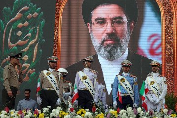 Iranian army soldiers stand in front of a picture of Iran’s supreme leader Ayatollah Mojataba Khamenei during a rally. (Source: Getty Images)
