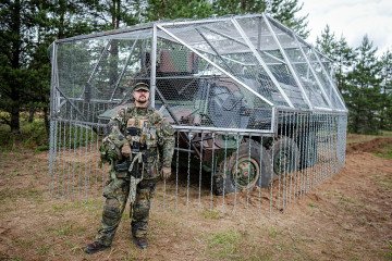 Bundeswehr soldier Marcus stands next to a Fuchs armored personnel carrier in front of the makeshift drone defense cage he designed and built himself during the “Freedom Shield 2026” combat exercise in Lithuania. (Source: Getty Images)