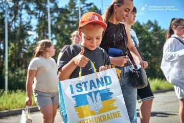 A child holds a bag reading “I Stand With Ukraine” during an event in Ukraine. (