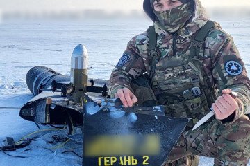 A Ukrainian soldier poses with debris from a downed Russian Geran-2 (Shahed) drone, intercepted by a Sting drone in a snowy field. (Photo: Wild Hornets)