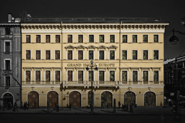 An illustration depicting LVMH’s Grand Hotel Europe split between Louis Vuitton branding and military camouflage, highlighting its continued service to sanctioned Russian defense clients. (Source: Source: UNITED24 Media/Oleksandr Manukians)