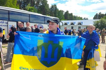 Ukrainian soldiers with national flags draped over their shoulders after returning home in Ukraine, on June 26, 2026. (Source: Coordination Headquarters for the Treatment of Prisoners of War)