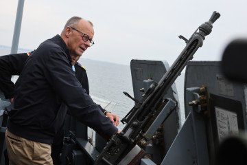 Federal Chancellor Friedrich Merz stands next to an MG 3 machine gun during his inaugural visit to the navy on board the frigate “Bayern” in Rostock, Mecklenburg-Western Pomerania, on August 28, 2025. (Source: Getty Images)