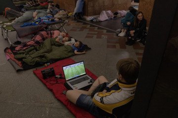 A person watches on a laptop the FIFA World Cup 2026 Round of 32 match between Belgium and Senegal as people take shelter at a metro station during Russian air attacks on Kyiv, early on July 2, 2026. (Source: Getty Images)