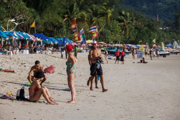 Visitors sit and walk along Patong Beach in Phuket, Thailand. (Source: Getty Images)