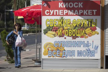 Russia Struggles to Supply Temporarily Occupied Crimea as Essential Goods Disappear From Shelves A pedestrian carries grocery bags past a supermarket advertisement written in Russian cyrillic script in Limassol, Cyprus, on April 8, 2014. Illustrative photo. (Source: Getty Images)