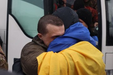 A heartfelt embrace between two recently freed individuals, as one is wrapped in the Ukrainian flag. (Photo: Volodymyr Zelenskyy)