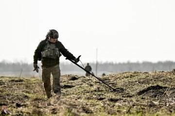 A sapper from the 808th Pontoon-Bridge Brigade of the Ukrainian Support Forces scans the ground with a metal detector while clearing the deoccupied territory of the Kherson region in Ukraine on November 22, 2025. (Source: Getty Images)