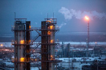 A gas flare burns beyond petroleum cracking towers at the Lukoil-Nizhegorodnefteorgsintez oil refinery, operated by OAO Lukoil, in Nizhny Novgorod, Russia. (Source: Getty Images)