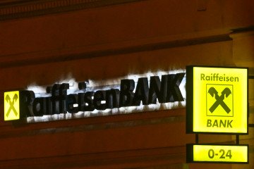 The illuminated yellow logo and '0-24' ATM signage of Raiffeisen Bank. (Source: Getty Images)