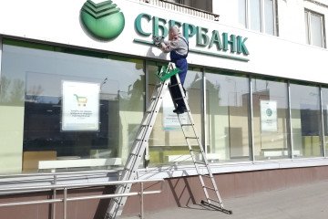 A worker installs a sign on the Sberbank's branch building April 1, 2024, in Moscow, Russia.