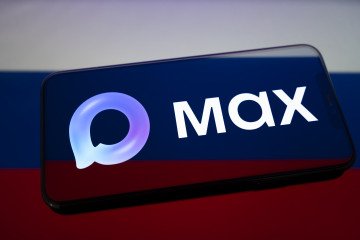 The Max logo appears on a smartphone screen placed on a reflective surface onto which the Russian flag is projected on February 16, 2026. (Source: Getty Images)