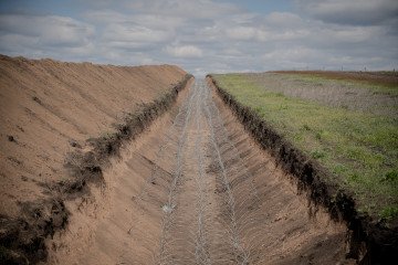 This photograph shows a barbed wire defense line running across a field at an undisclosed location on May 1, 2026 This photograph shows a barbed wire defense line running across a field at an undisclosed location on May 1, 2026