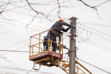 An electrician on a lifting platform repairs a power line damaged by a Russian drone strike on March 25, 2026 in Kharkiv, Ukraine. (Source: Getty Images)