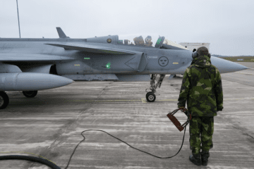 A Swedish Air Force ground crew member stands next to a JAS 39 Gripen fighter jet in Kallinge, Sweden. (Source: Reuters)