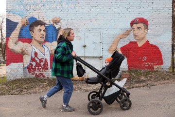 A woman pushes a baby stroller past patriotic graffiti featuring the Russian flag in Krasnogorsk, a suburb of Moscow, Russia, on April 10, 2023. (Source: Getty Images)