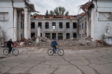 Vecinos de Kostiantynivka cabalgan junto a un edificio alcanzado por un ataque ruso. Vecinos de Kostiantynivka cabalgan junto a un edificio alcanzado por un ataque ruso.