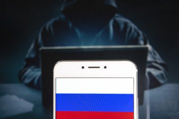 Russian Federation flag is seen on an Android mobile device with a figure of hacker in the background. Illustrative photo. (Source: Getty Images)