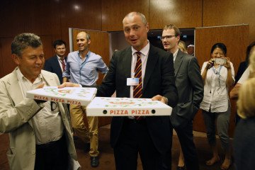 Alexander Zorin, a member of the Russian delegation, carries pizza to journalists waiting outside a late-night press conference in Geneva on September 9, 2016. (Photo: Getty Images)