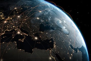 View of planet Earth from space showing illuminated cities at night and glowing connection lines across Europe, the Middle East, and parts of Asia. Illustrative image. (Source: Getty Images)