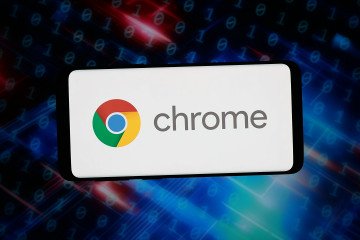 The logo of web browser Google Chrome is displayed on a smartphone in front of abstract background on computer screen. (Source: Getty Images)