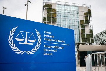 This photograph shows the International Criminal Court (ICC) in the background with its logo on a sign in the foreground in The Hague, on February 23, 2026. (Source: Getty Images)