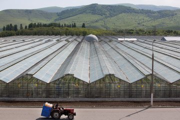 A farm worker drives a tractor past Soviet era hothouses used to grow vegetables at the Yuzhny Agricultural Complex, Russia, on May 18, 2016.