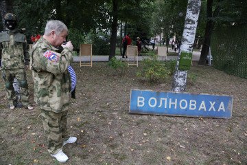 A member of Russian forces poses with a road sign looted from the occupied Ukrainian town of Volnovakha during a pro-war event in Lubertsy, a suburb of Moscow, September 2023. (Source: Getty Images)