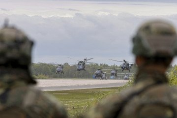 Soldiers look at German Air Force helicopters taking off at the airfield of Pajuostis in Panevezis, Lithuania, on May 6, 2025, during the “Griffin Lightning 2025” military exercises. (Source: Getty Images)