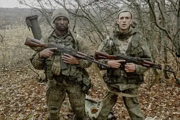 Two foreign mercenaries recruited by Russia pose with assault rifles before being sent to the front. (Photo: HUR)