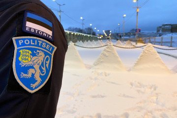 An Estonian police officer stands on the bridge connecting Narva and Russia, with the national flag and police emblem visible on his uniform. (Source: Getty Images)