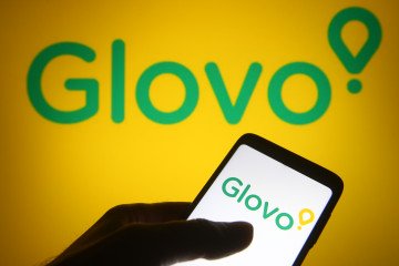 Glovo lanza pagos diferidos para salvar a comercios ucranianos Logotipos de Glovo y eDilo sobre un fondo tecnológico digital que representa servicios financieros y de entrega.