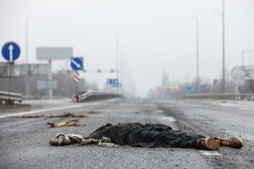 A civilian lies dead on the E40 highway near Kyiv, April 2022, after Russian forces killed hundreds of people attempting to flee the area. (Source: Getty Images)