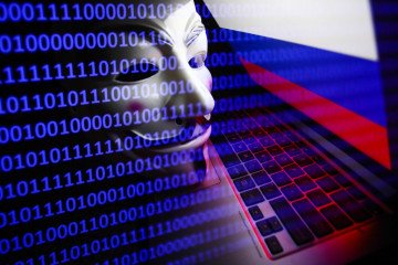 Russian flag displayed on a laptop screen, Guy Fawkes mask and binary code displayed on a screen are seen in this multiple exposure illustration photo taken in Krakow, Poland on March 1, 2022. (Source: Getty Images)
