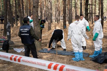 Investigators, including workers from the "war crime prosecutors, Kharkiv region, are seen at the mass burial site. Illustrative photo. (Source: Getty Images)