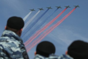 Security personnel watch as Russian air force fighter jets trail the colors of the Russian flag.  (Source: Getty Images)