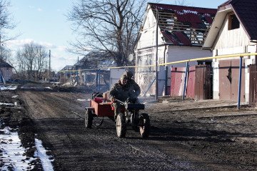 Russian soldiers ride a walk-behind tractor past destroyed homes in Kazachya Loknya, Kursk region, following recent fighting. (Source: Getty Images)