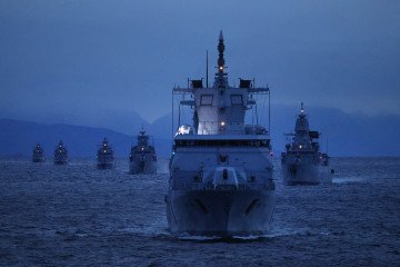 Ships of the German Navy, including the “Baden-Wuerttemberg” frigate (in foreground), sail at twilight during the Andoya “Missile Firing Exercise 2025” military exercise in the North Sea on October 13, 2025, near Harstad, Norway. (Source: Getty Images)