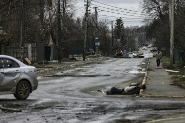 A man walks on a street with several dead bodies on the ground in Bucha, northwest of Kyiv, as Ukraine says Russian forces are retreating from northern areas around Kyiv and the city of Chernihiv, on April 2, 2022. (Source: Getty Images)